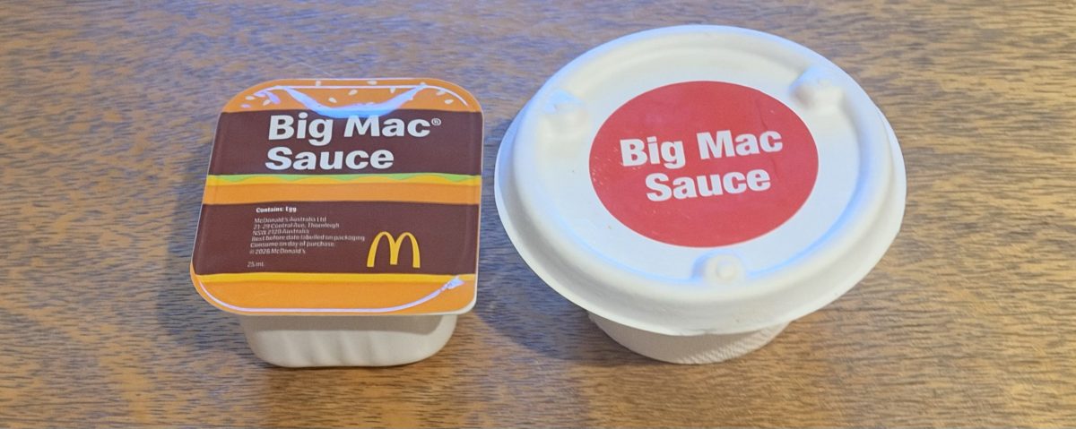 A sealed Big Mac Sauce tub with Big Mac artwork next to a white cardboard sauce cup with a red Big Mac Sauce sticker on the lid