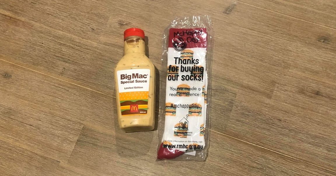 A 500ml Limited Edition Big Mac Special Sauce bottle beside a packet of McHappy Day Big Mac socks on a timber floor