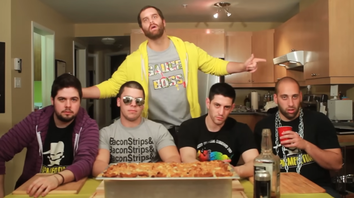 The Epic Meal Time crew posing around a kitchen table behind a large tray of their finished Fast Food Lasagna