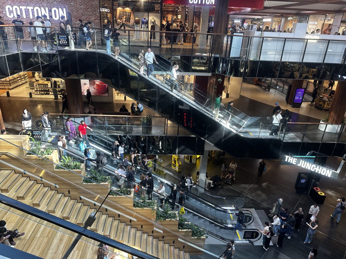 Overhead view of escalators and timber steps at Highpoint with Cotton On above and The Junction signage to the right