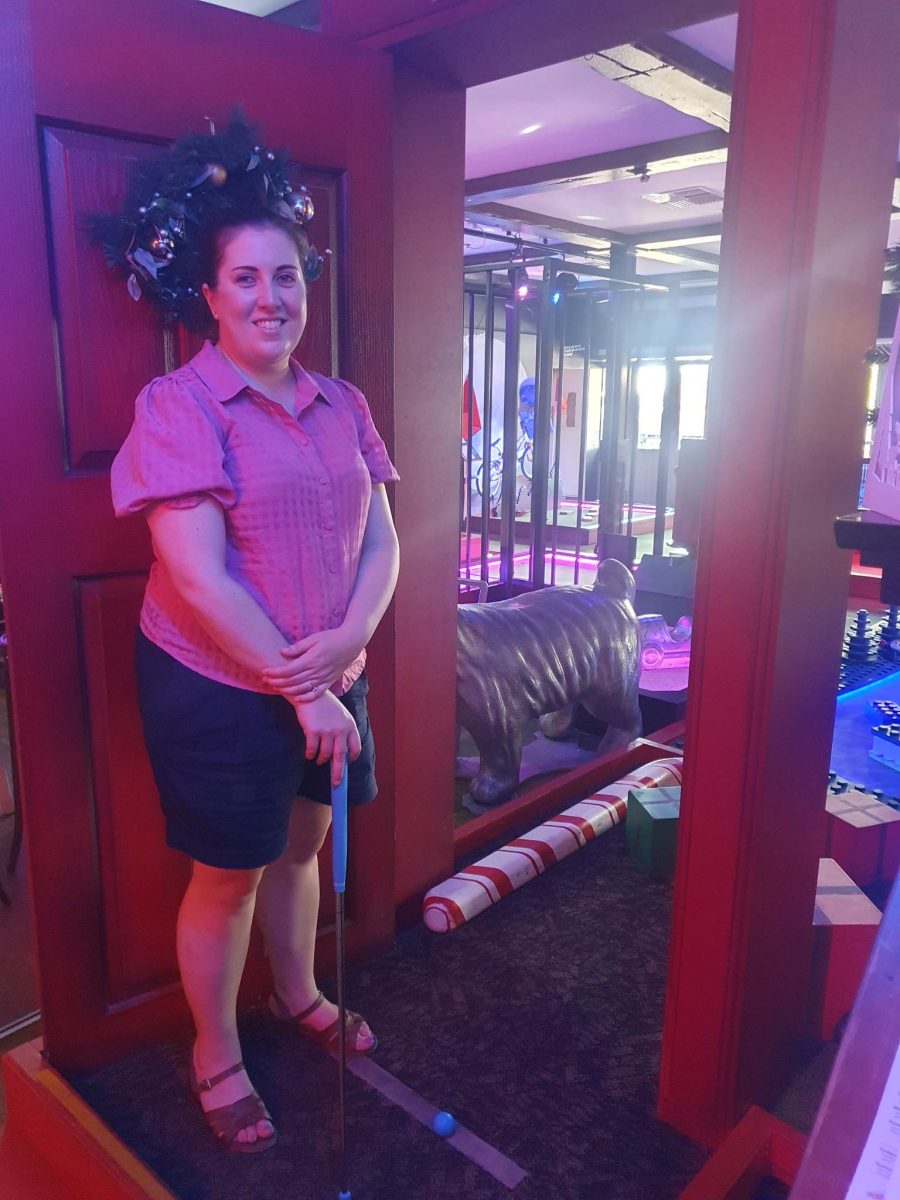 kate holding golf club at holey moley perth