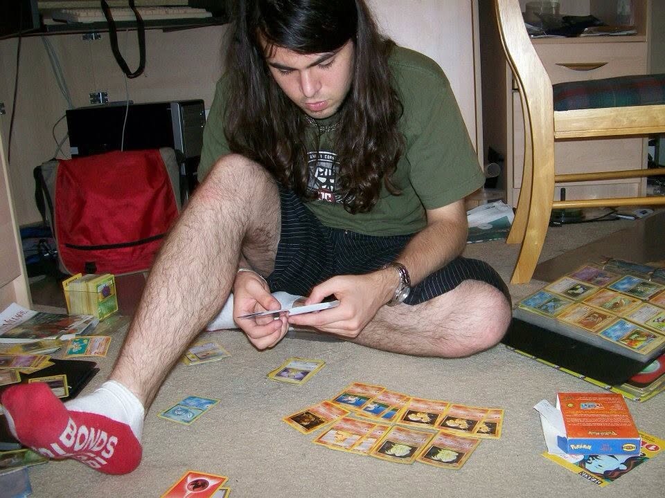Keith in 2009 sitting on the floor sorting through vintage Pokémon cards with binders and boxes spread around him