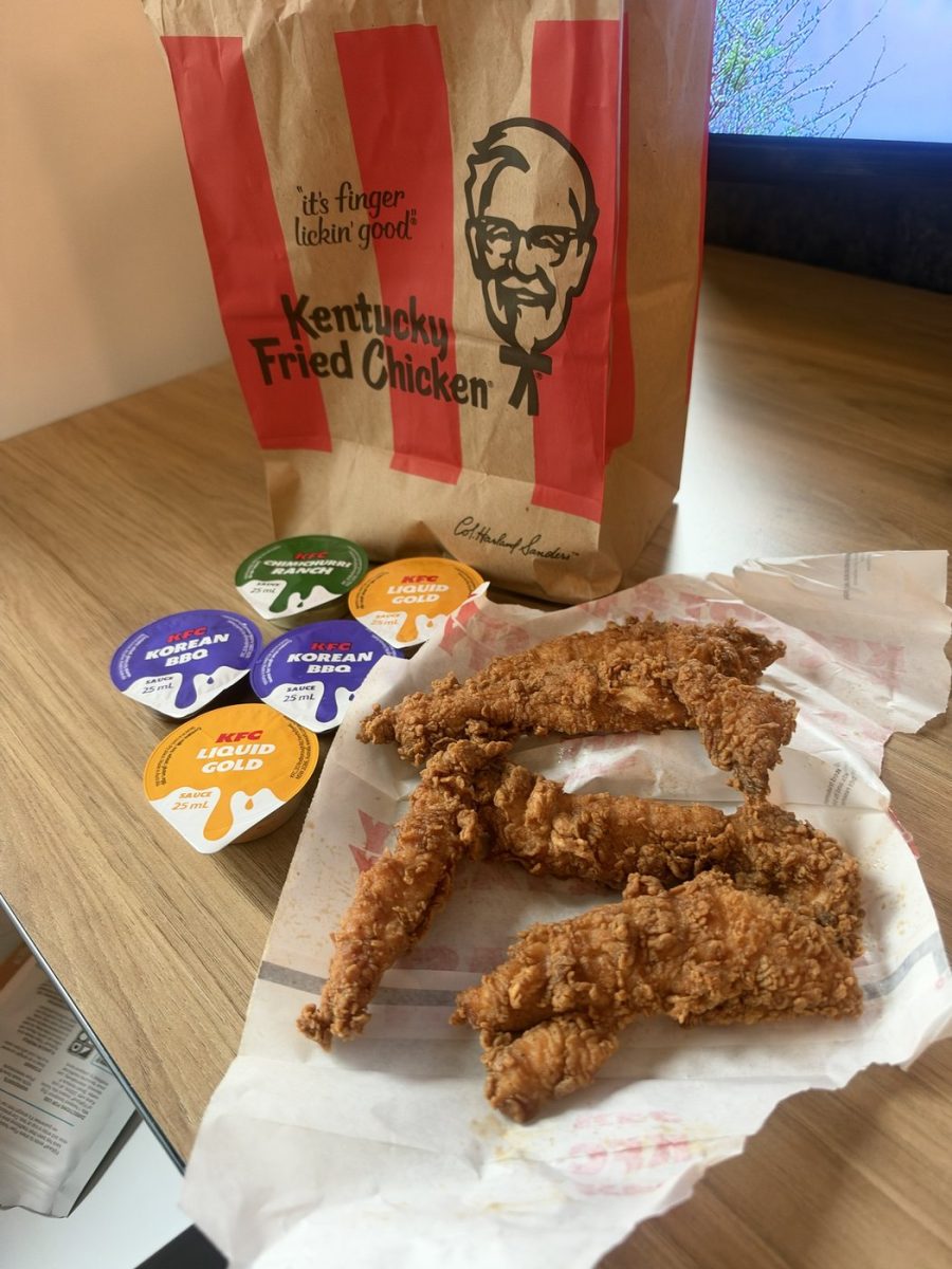 KFC bag with five 25 mL dipping sauce tubs (Chimichurri Ranch, Liquid Gold and Korean BBQ) beside three of the new tenders on paper