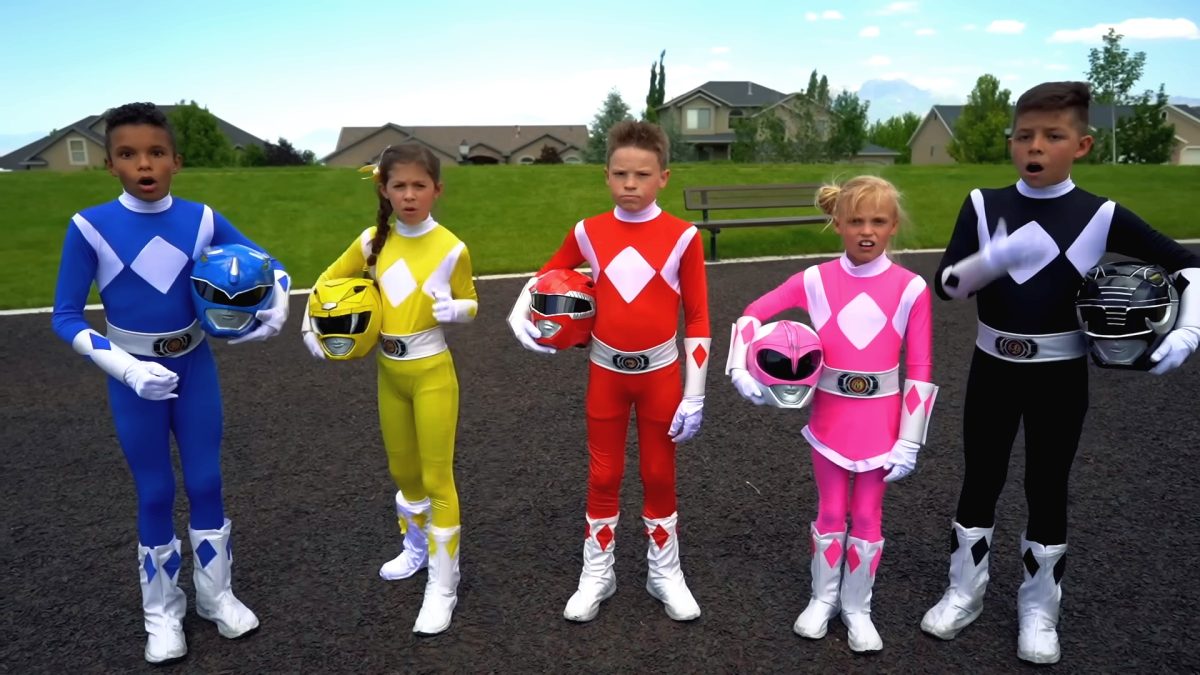 The five kids from Ninja Kidz TV's Power Rangers retelling standing in a row in blue, yellow, red, pink and black ranger costumes, holding their helmets